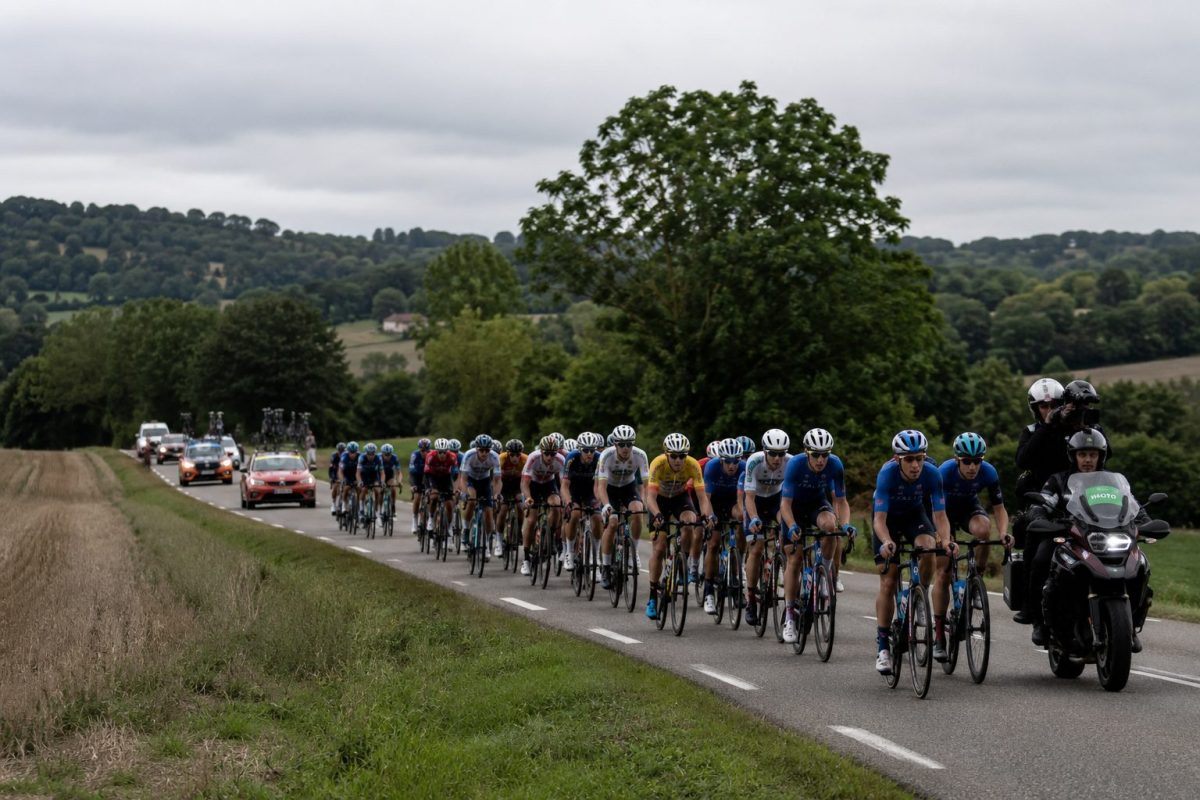Peloton de jeunes coureurs cyclistes engagé sur une route de campagne française lors de la troisième étape du Tour de l’Avenir 2026 entre Vierzon et Saint-Vallier.