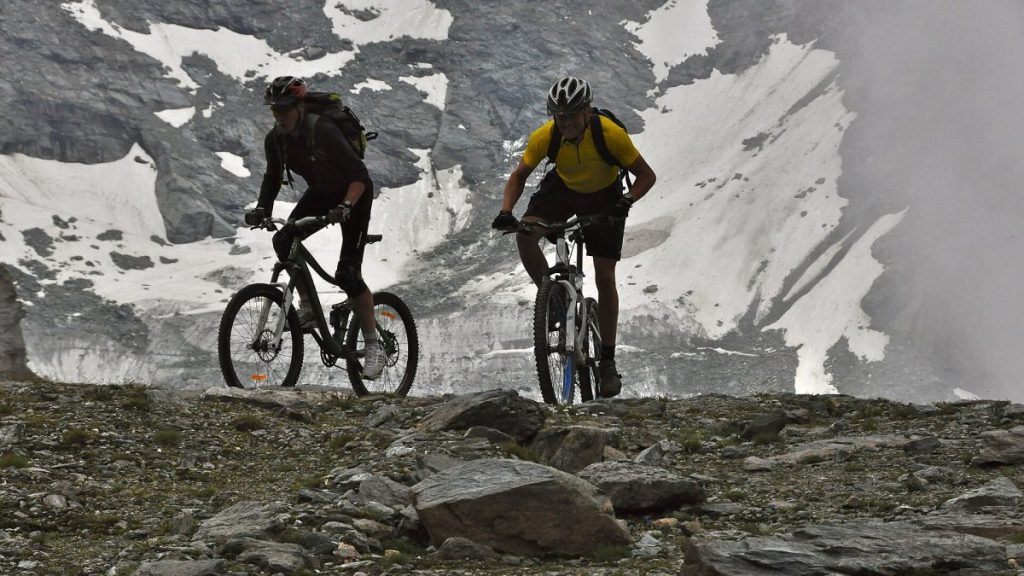 Deux vététistes à Verbier avec, en arrière plan, des névés.