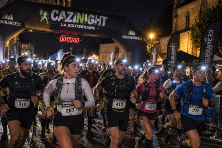 Départ nocturne de la Cazinight 2026 à La Souterraine, avec des traileurs portant des dossards, des lampes frontales et des tenues de trail sous l'arche de départ.